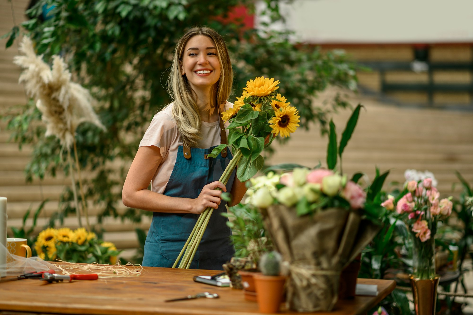 Florist standing and holding bouquet of sunflowers in flower shop